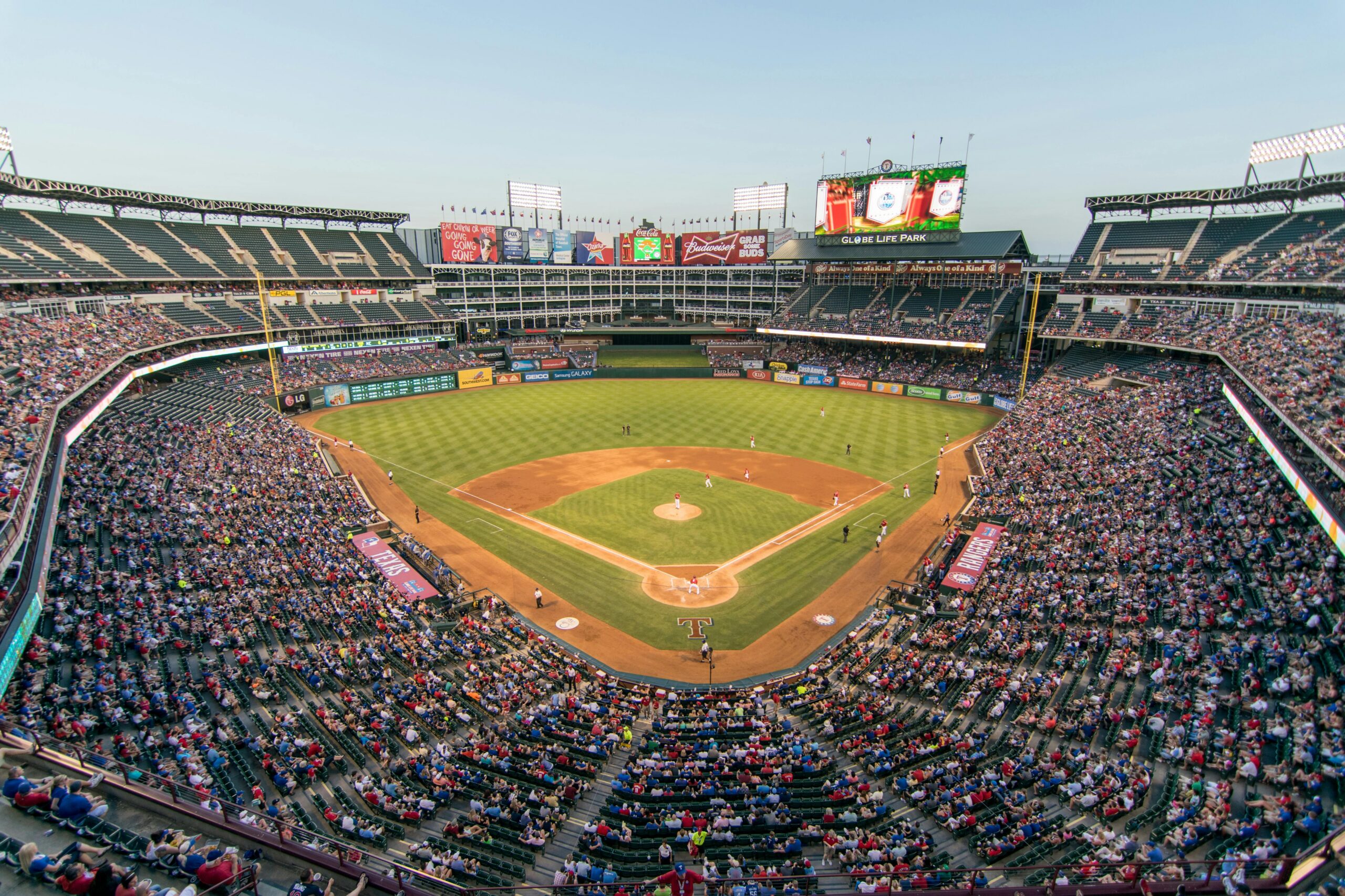 圣经是谁写的? Aerial view of a lively baseball game at the iconic Globe Life Park filled with cheering fans.