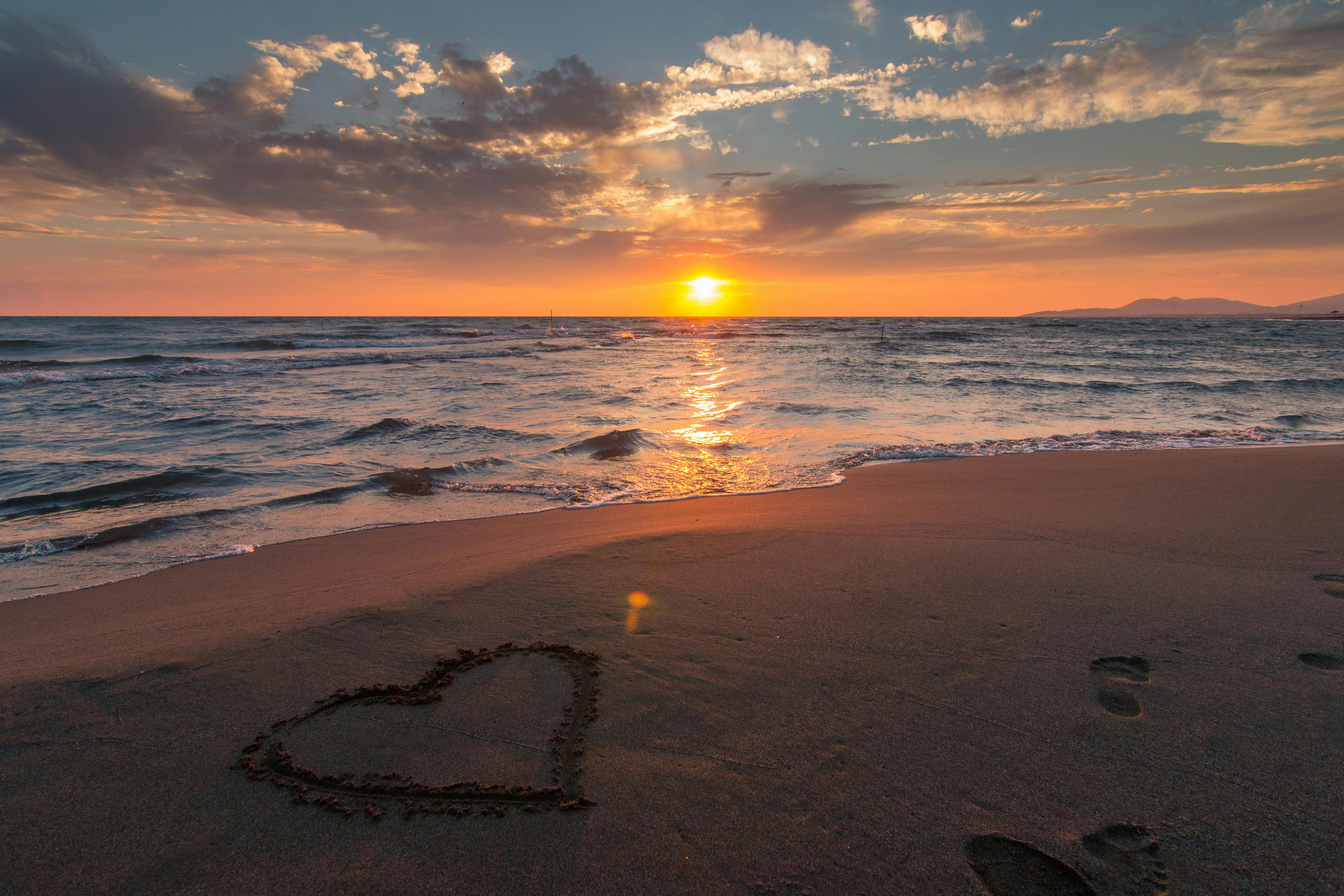 科学与信仰冲突吗? Beautiful sunset over ocean with a heart shape in the sand, perfect for romantic themes.